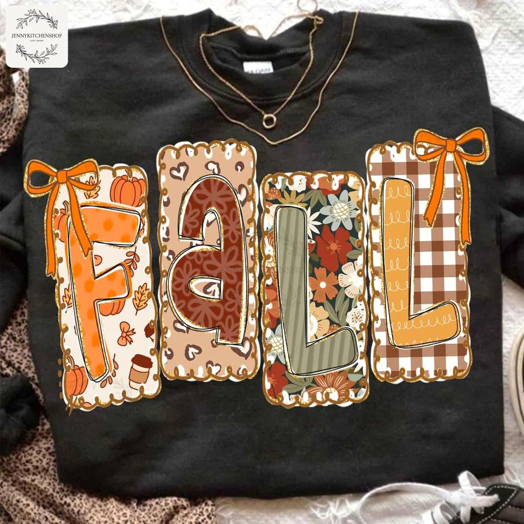 A black sweatshirt featuring the word FALL in coquette style letters, styled with a gold necklace and leopard print accessory.