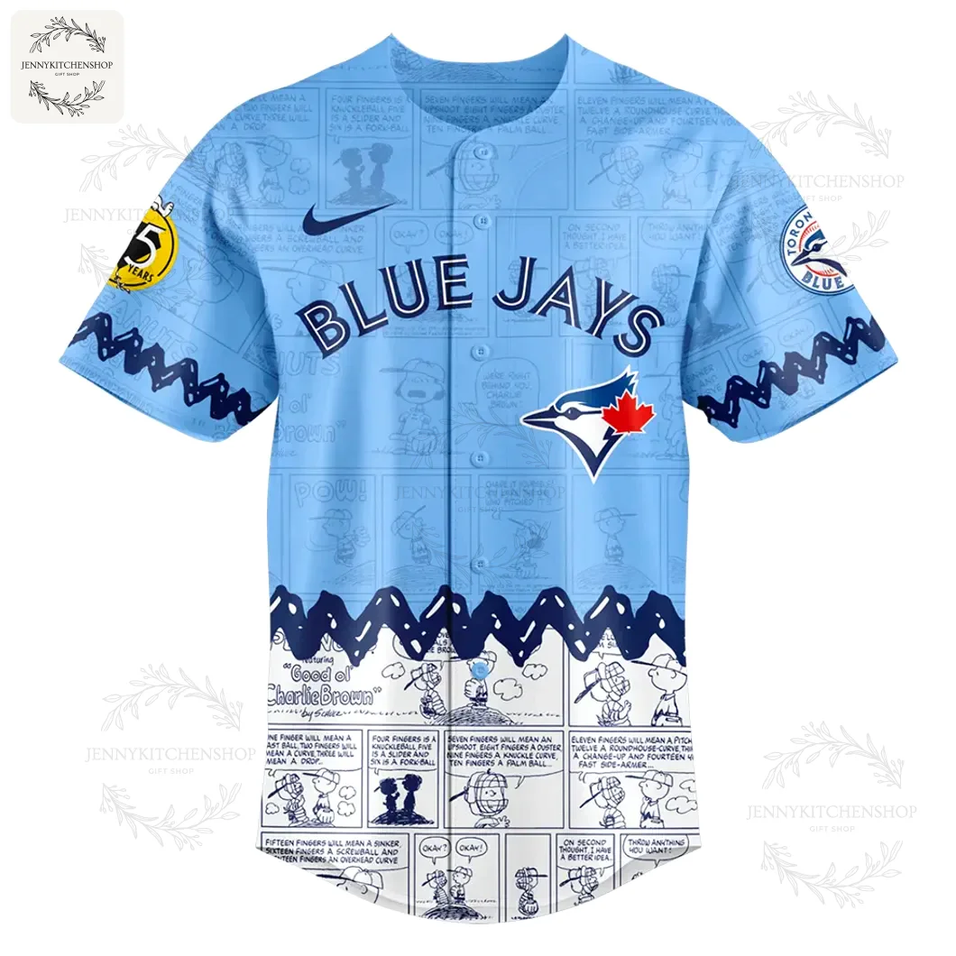Front of the light blue Blue Jays Peanuts Day jersey, with 'BLUE JAYS' text, team logo, and a Peanuts comic strip pattern at the bottom.