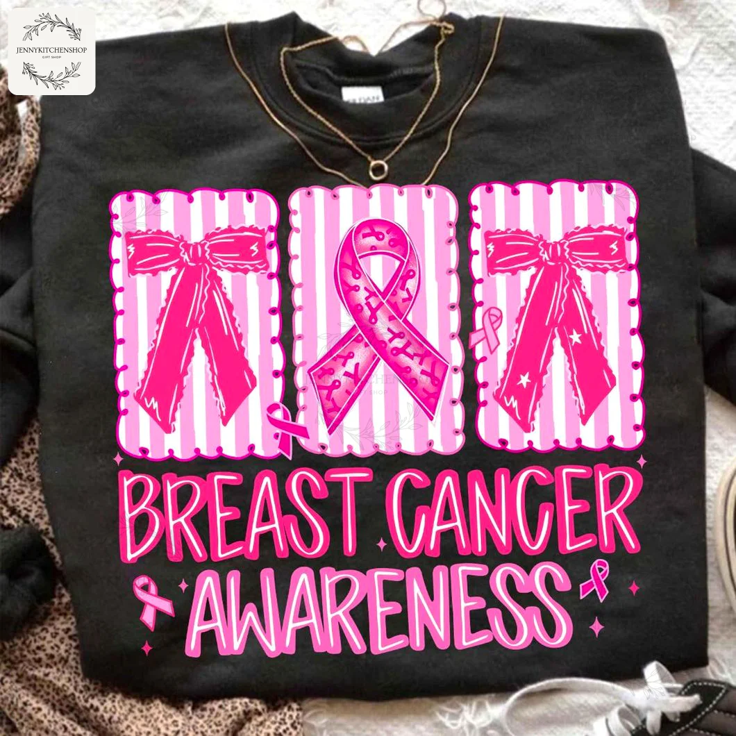 A black t-shirt with a 'Breast Cancer Awareness' design featuring pink coquette bows and a pink ribbon on striped panels.