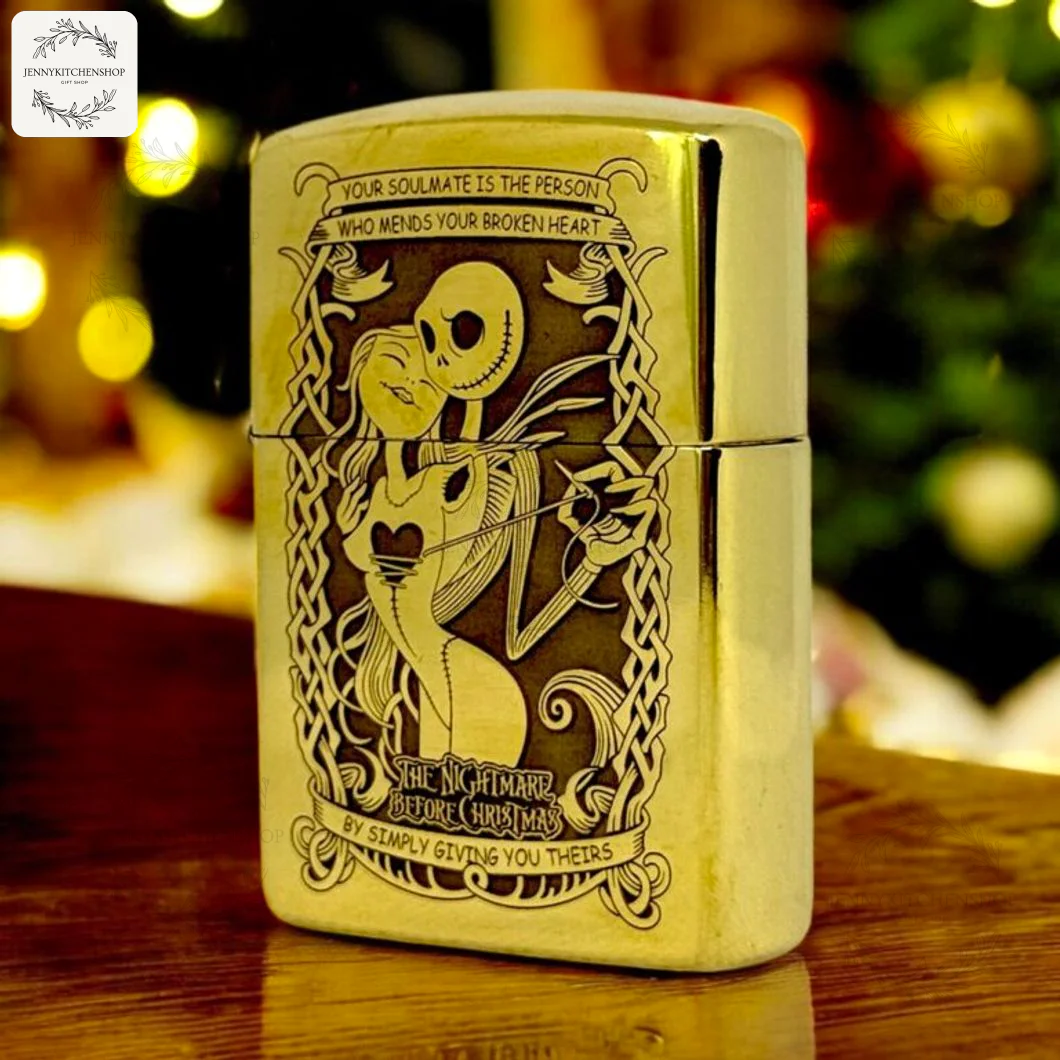 Front view of the gold Nightmare Before Christmas lighter case, showing the Jack and Sally engraving against a blurry Christmas tree.
