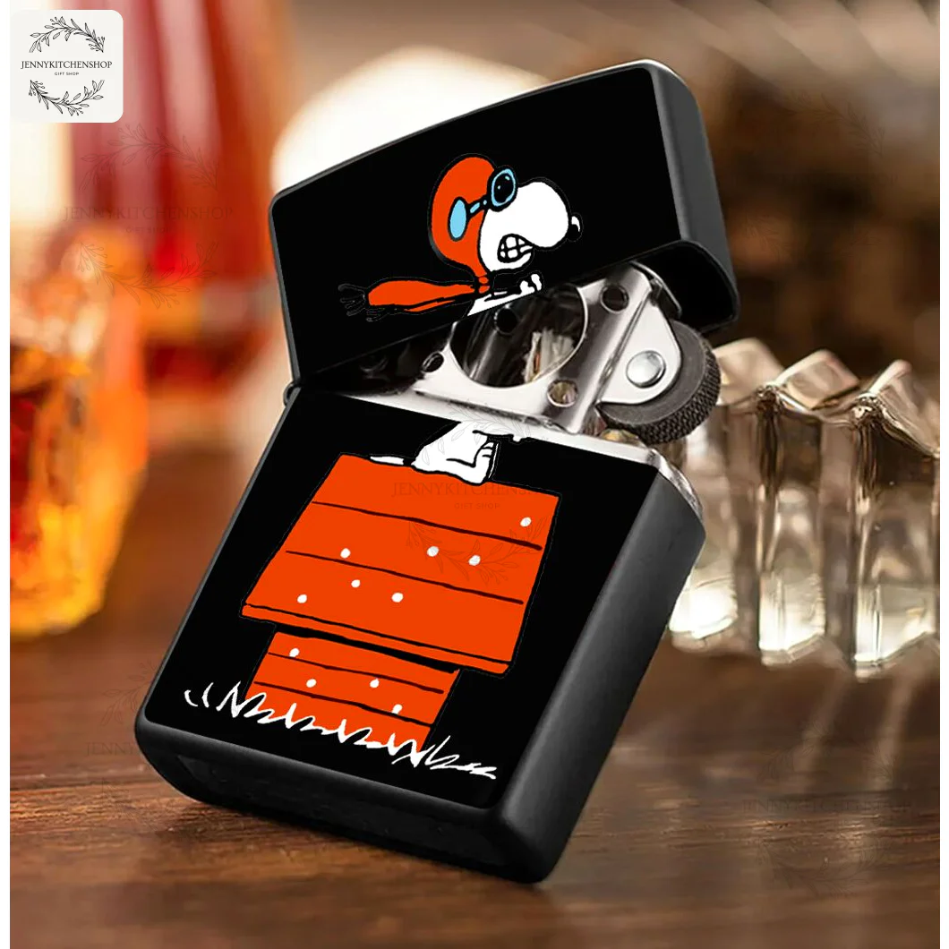 The Snoopy Red Baron windproof lighter case sits open on a wooden surface, displaying its classic metal lighter insert.