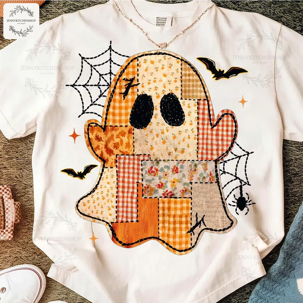 A white t-shirt featuring a preppy patchwork ghost design with floral and gingham patterns, surrounded by spiderwebs and bats.