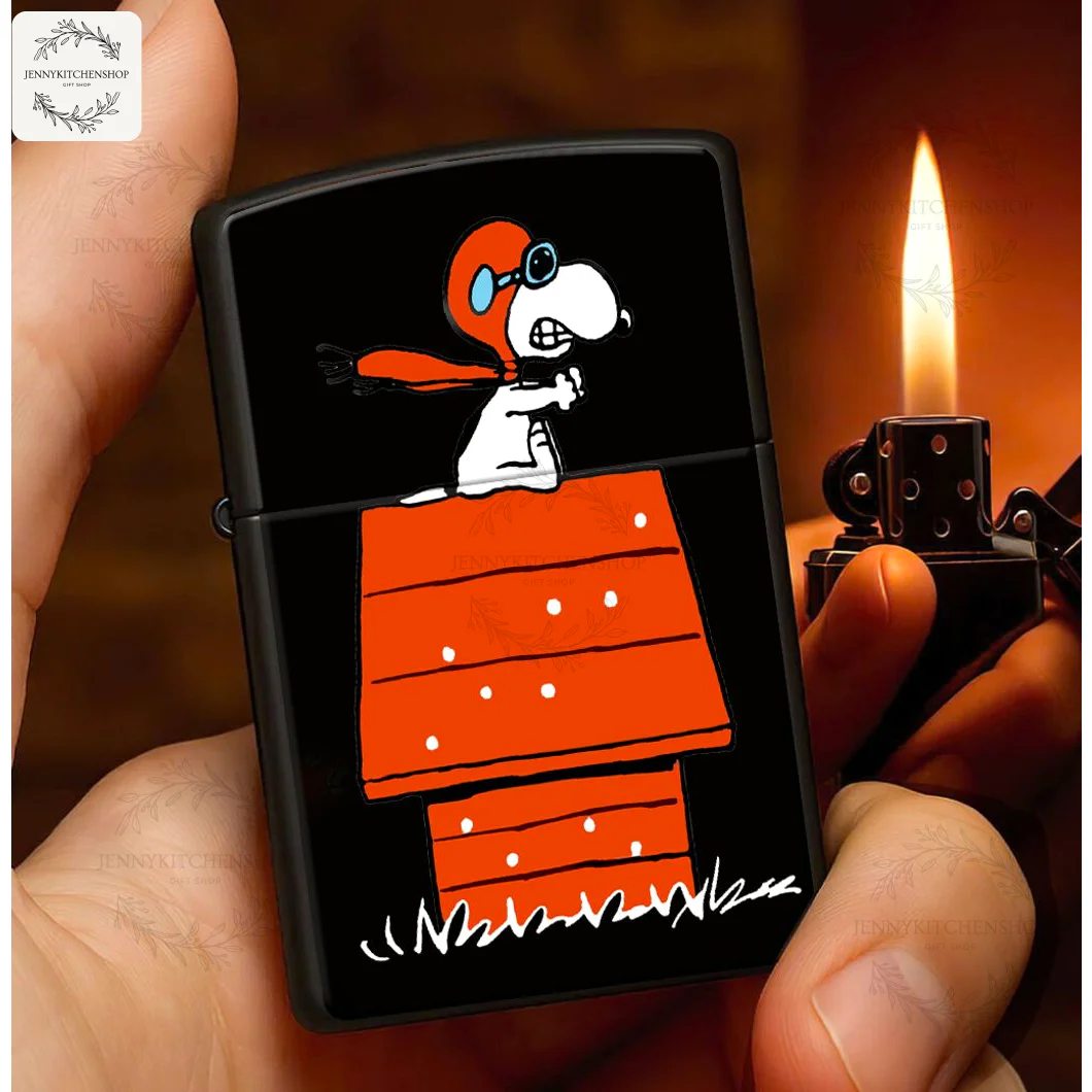 A hand holds a lit black windproof lighter featuring Snoopy as the World War I Flying Ace on his red doghouse.