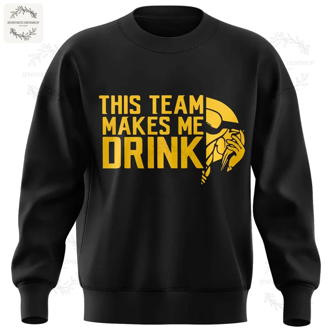The front of the black Minnesota Vikings sweatshirt with the gold text "This Team Makes Me Drink" and a stylized team logo.