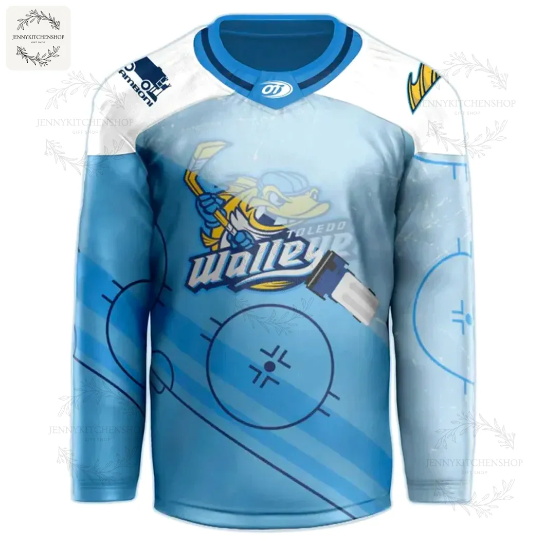 Front view of light blue Toledo Walleye hockey jersey with large Walleye mascot logo across the chest, stylized ice rink graphics, white shoulder yoke and blue collar