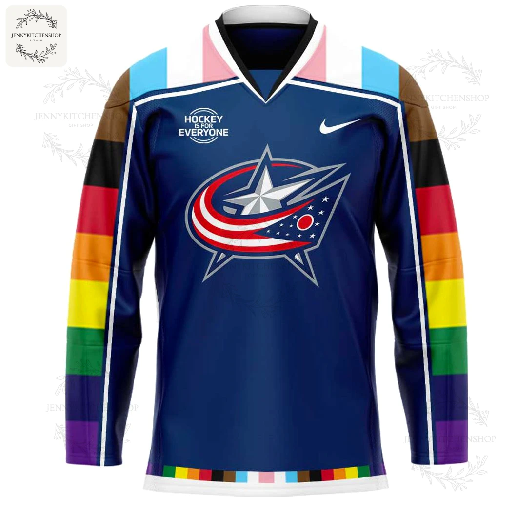 Close-up of the front of the Columbus Blue Jackets Pride jersey, showing the team logo and Progress Pride Flag colored sleeves.