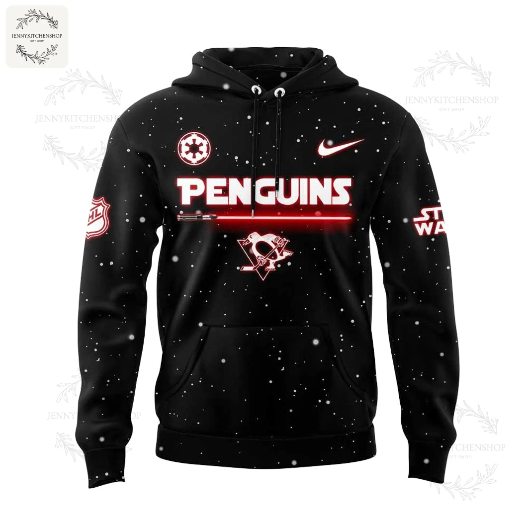 Front view of black hoodie with white snow-speckle print, prominent red-and-white PENGUINS text, lightsaber graphic across the chest, central penguin skull-and-sticks emblem and team/league sleeve patches.
